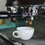 White Ceramic Mug on Espresso Machine Filling With Brown Liquid